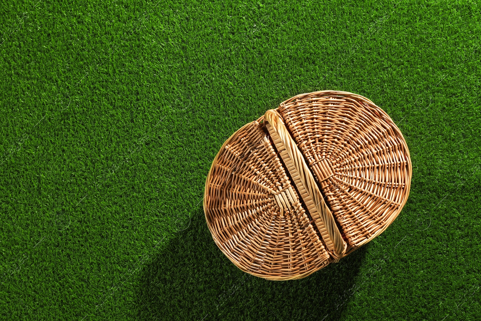 Photo of One picnic wicker basket on green grass, top view. Space for text