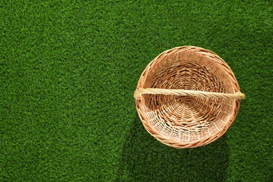 Photo of One picnic wicker basket on green grass, top view. Space for text