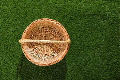 Photo of One picnic wicker basket on green grass, top view. Space for text