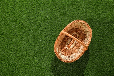 Photo of One picnic wicker basket on green grass, top view. Space for text