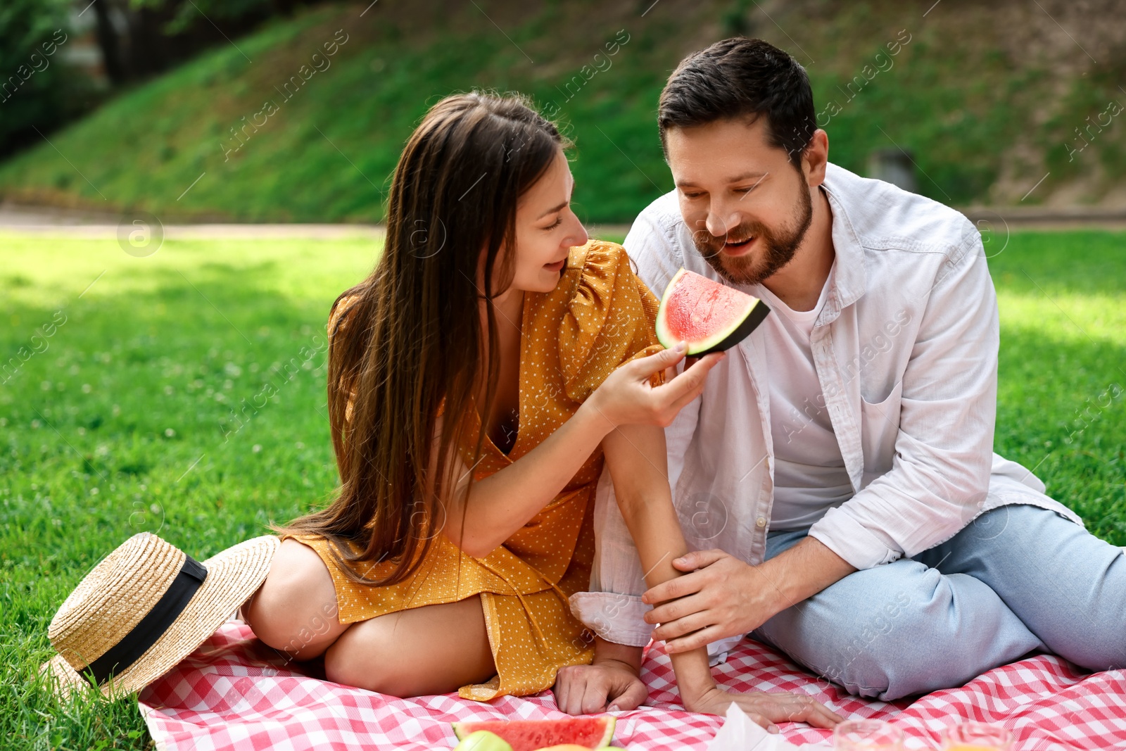 Photo of Lovely couple having picnic on green grass outdoors