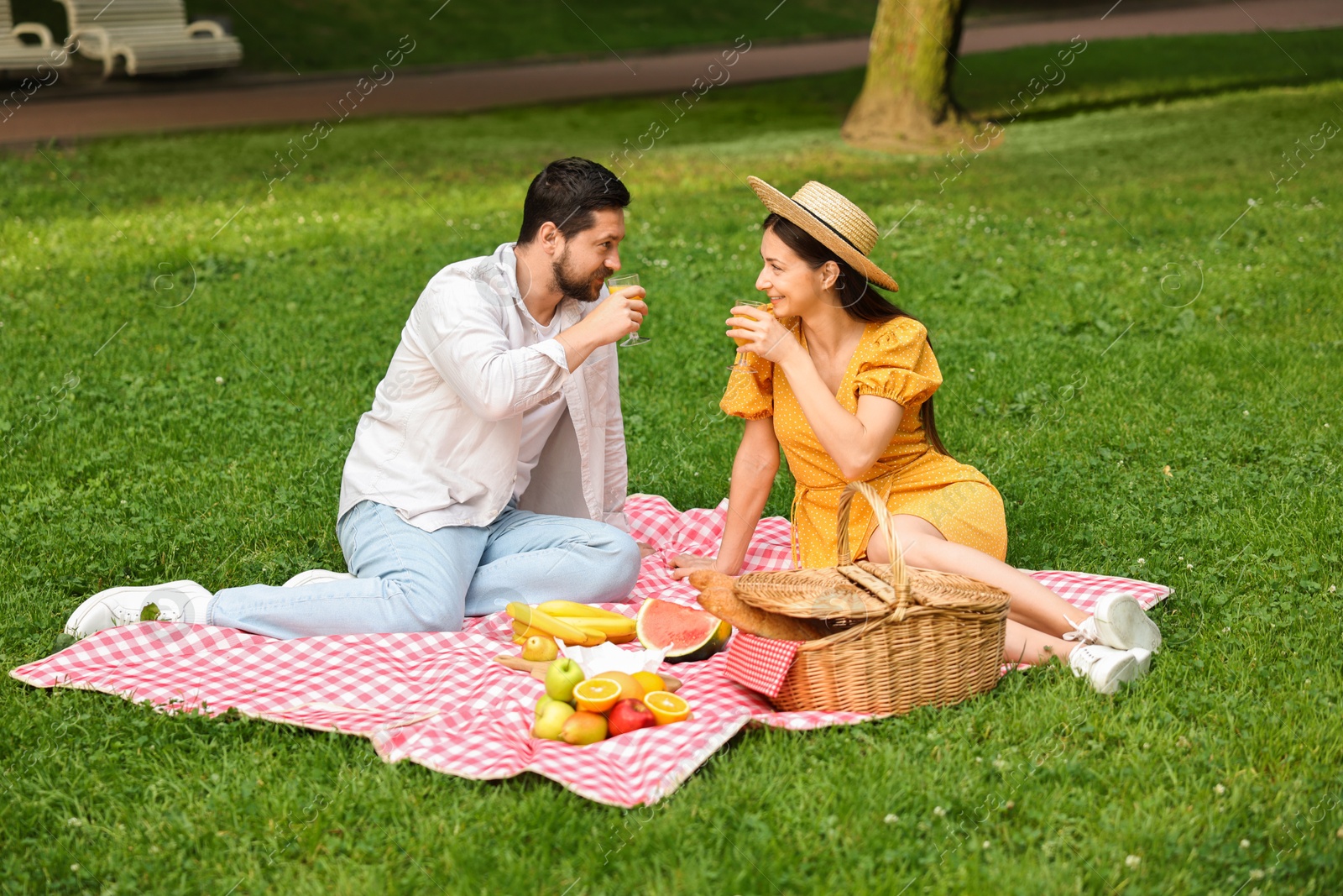 Photo of Lovely couple having picnic on green grass outdoors