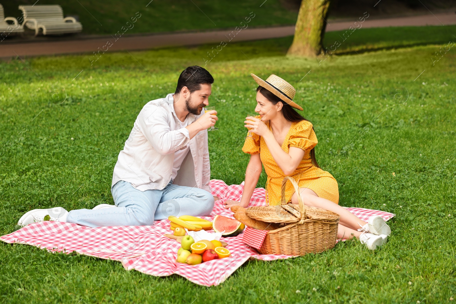 Photo of Lovely couple having picnic on green grass outdoors