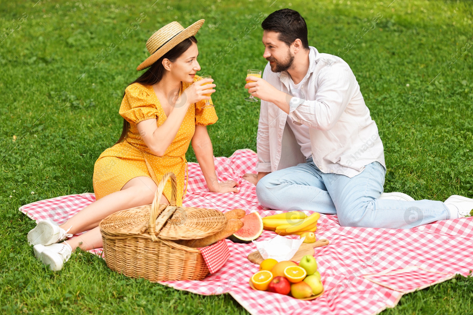 Photo of Lovely couple having picnic on green grass outdoors