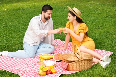 Lovely couple clinking glasses of juice on picnic blanket outdoors