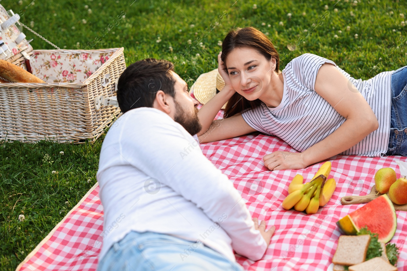 Photo of Lovely couple having picnic on green grass outdoors