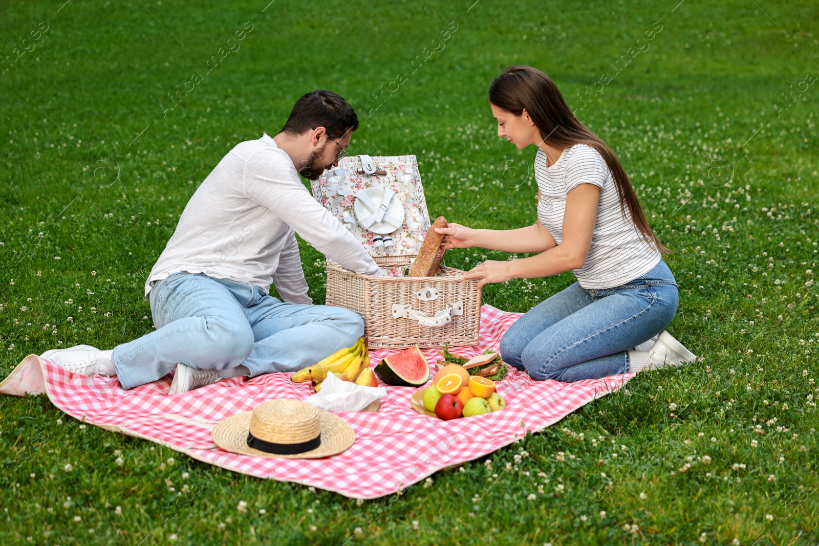 Photo of Lovely couple having picnic on green grass outdoors