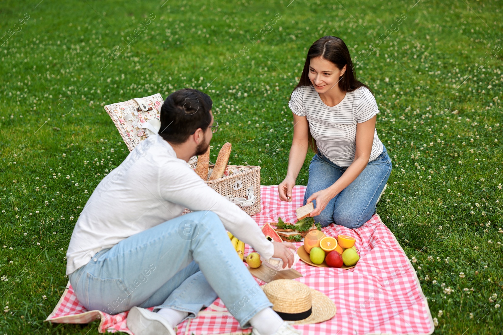 Photo of Lovely couple having picnic on green grass outdoors