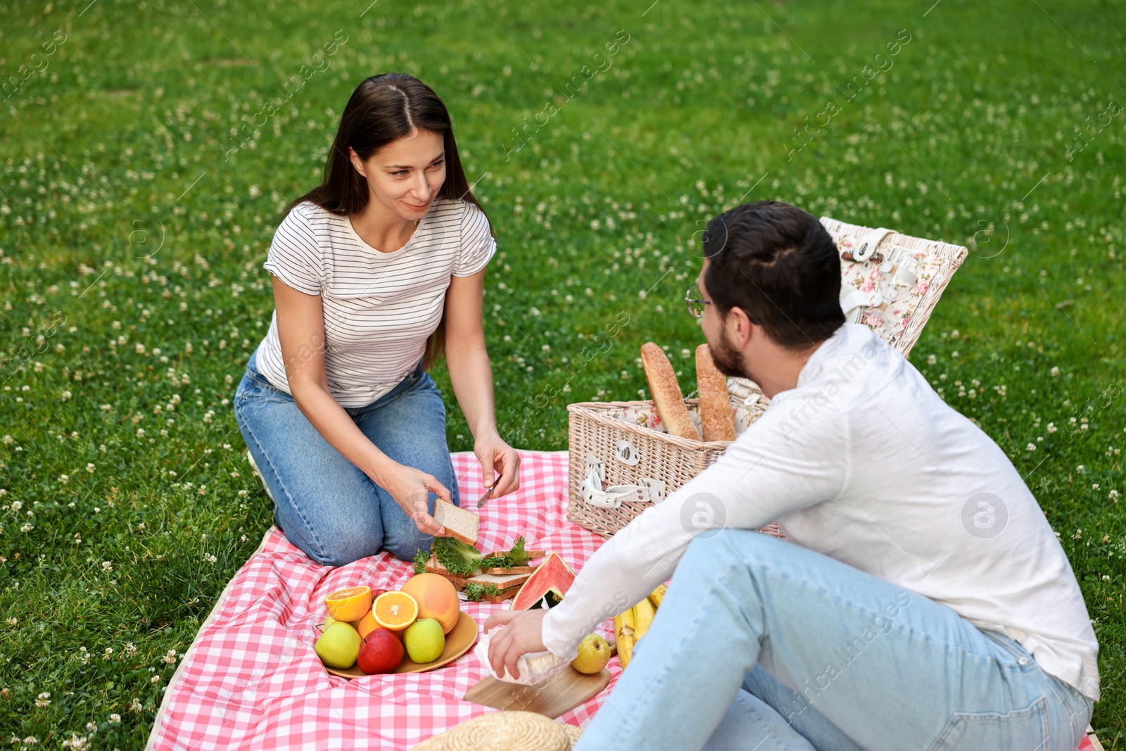 Photo of Lovely couple having picnic on green grass outdoors