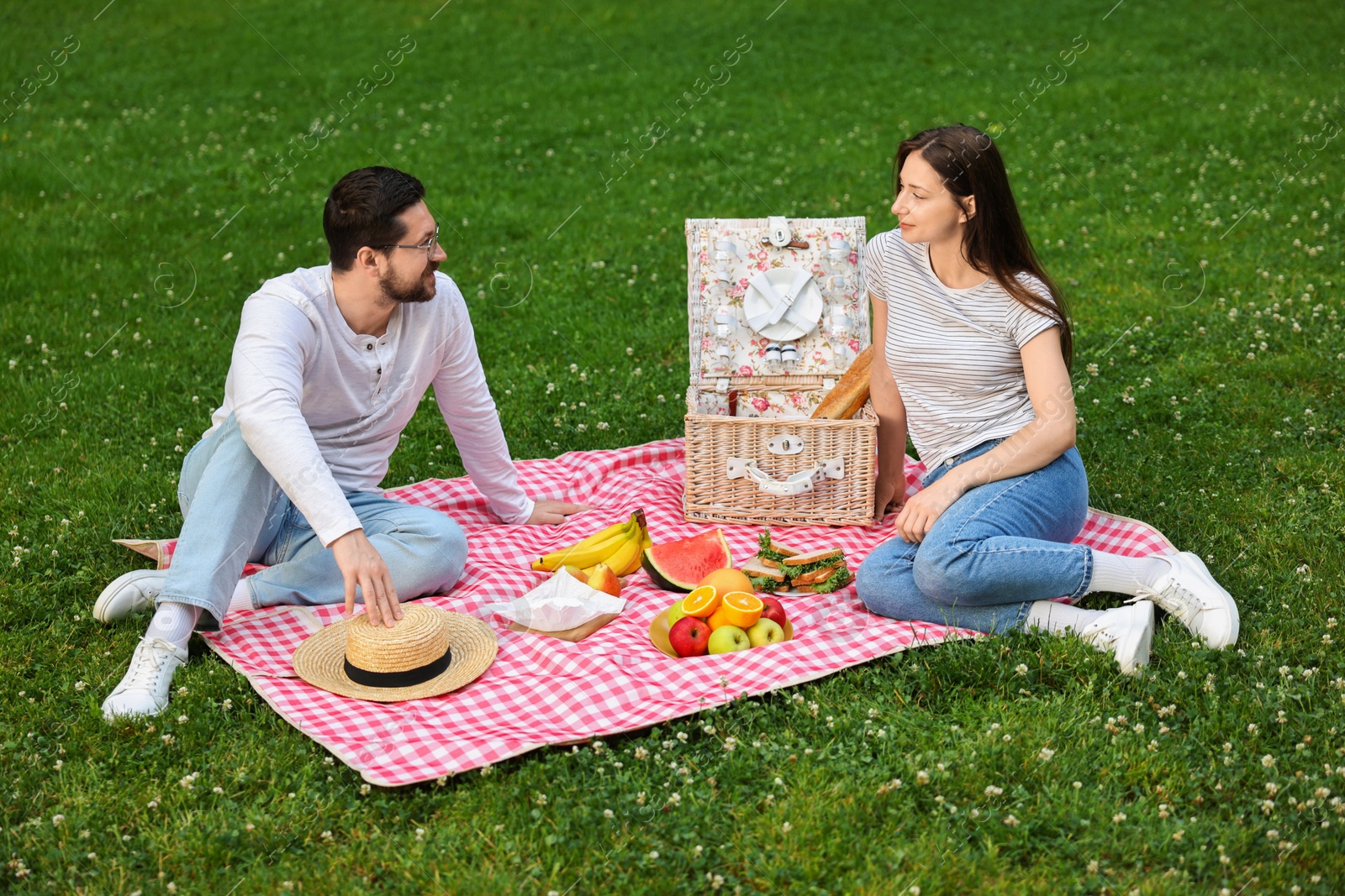 Photo of Lovely couple having picnic on green grass outdoors