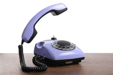 Photo of One violet telephone with handset on wooden table against white background