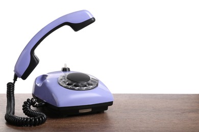 Photo of One violet telephone with handset on wooden table against white background