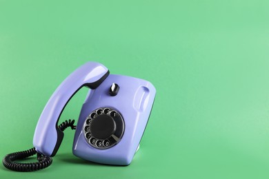 Photo of One violet telephone with handset on green background, space for text