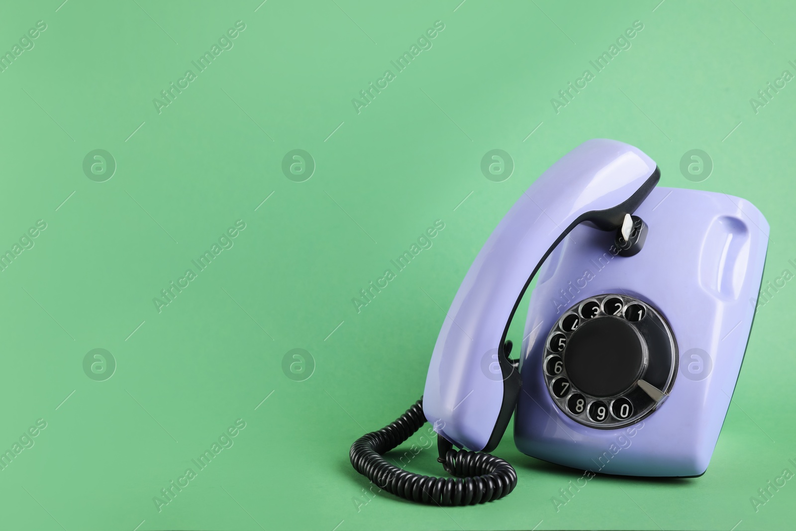 Photo of One violet telephone with handset on green background, space for text