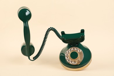 One green telephone with handset on beige background