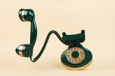 Photo of One green telephone with handset on beige background