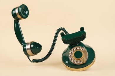 Photo of One green telephone with handset on beige background