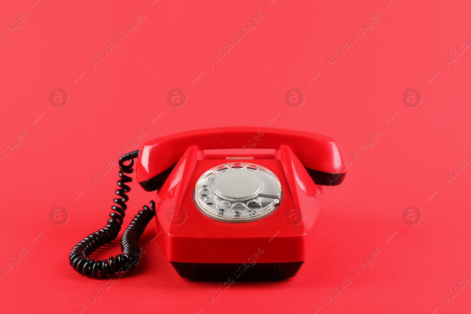 Photo of One telephone with handset on red background