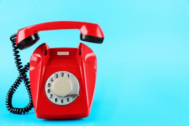 Photo of Red telephone with handset on light blue background, space for text