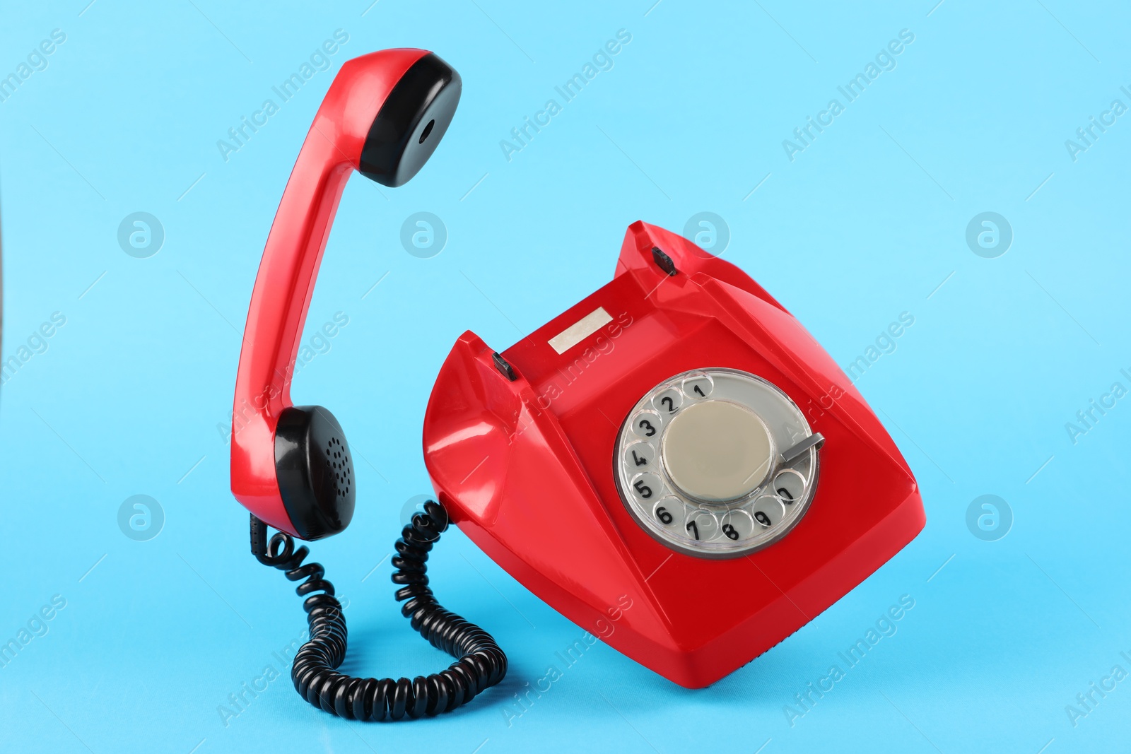 Photo of Red telephone with handset on light blue background