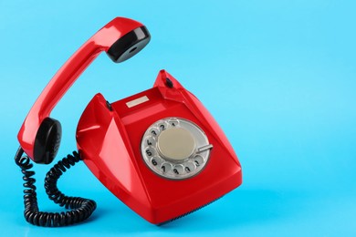 Photo of Red telephone with handset on light blue background, space for text