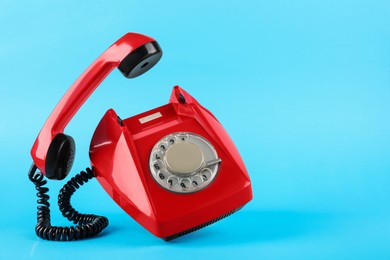 Red telephone with handset on light blue background, space for text