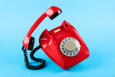 Photo of Red telephone with handset on light blue background