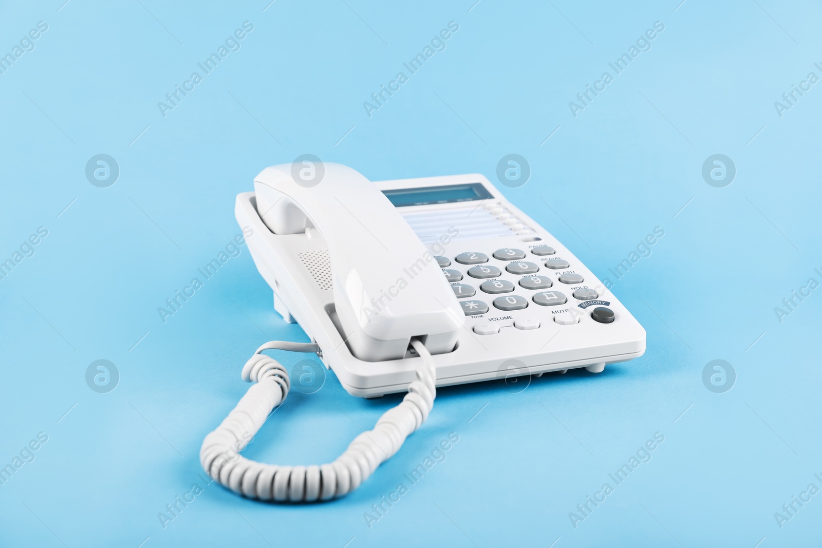 Photo of White telephone with handset on light blue background