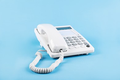 Photo of White telephone with handset on light blue background