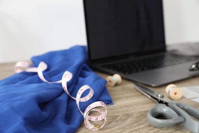 Photo of Laptop and different designer`s supplies on wooden table in workshop, selective focus