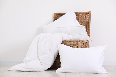 Clean pillows, duvet and storage basket on floor near white wall