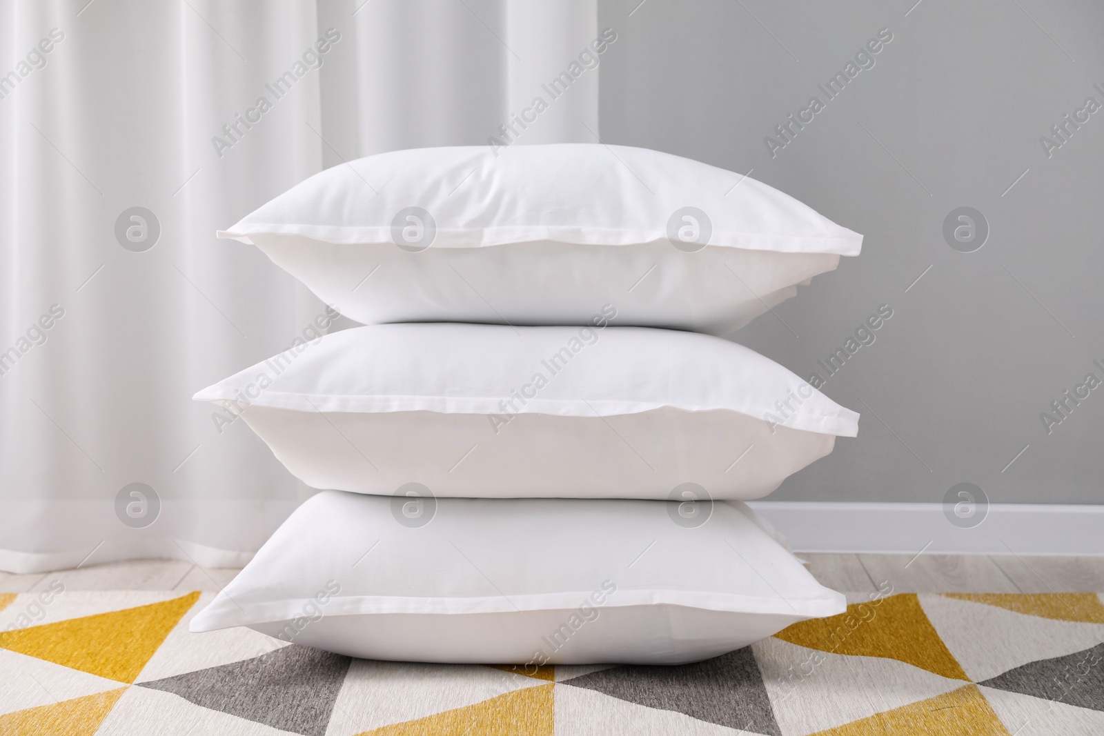 Photo of Stack of white pillows on floor indoors