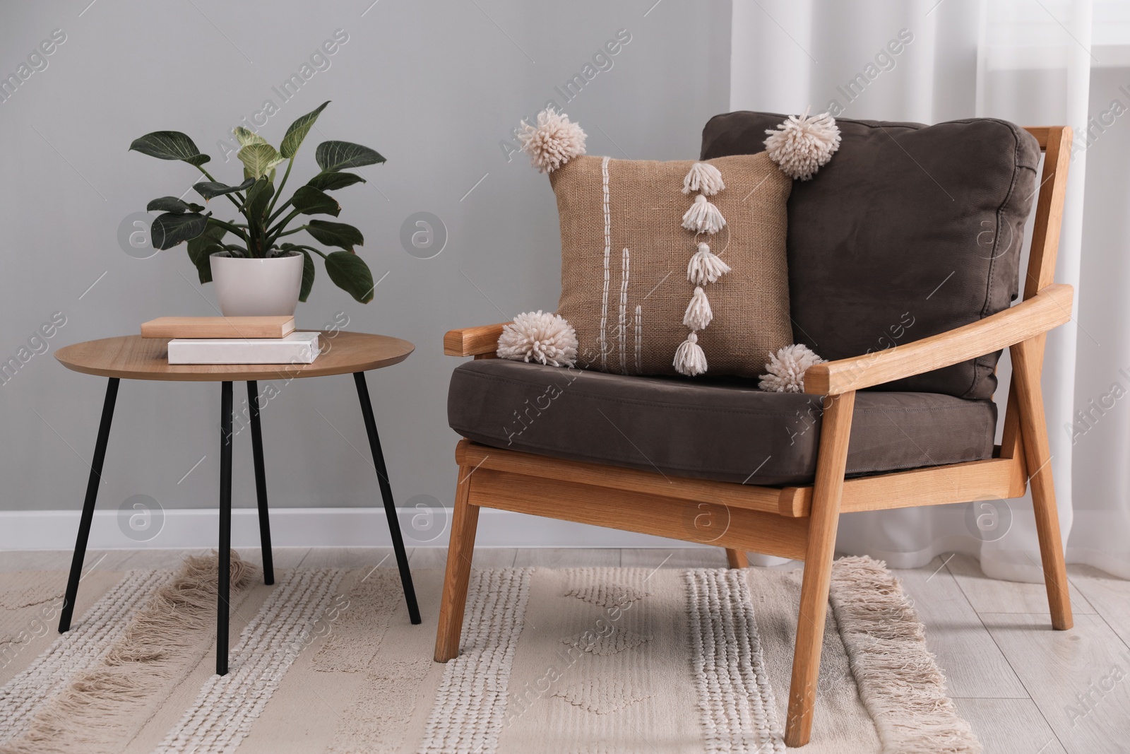 Photo of Soft pillow on armchair near coffee table indoors