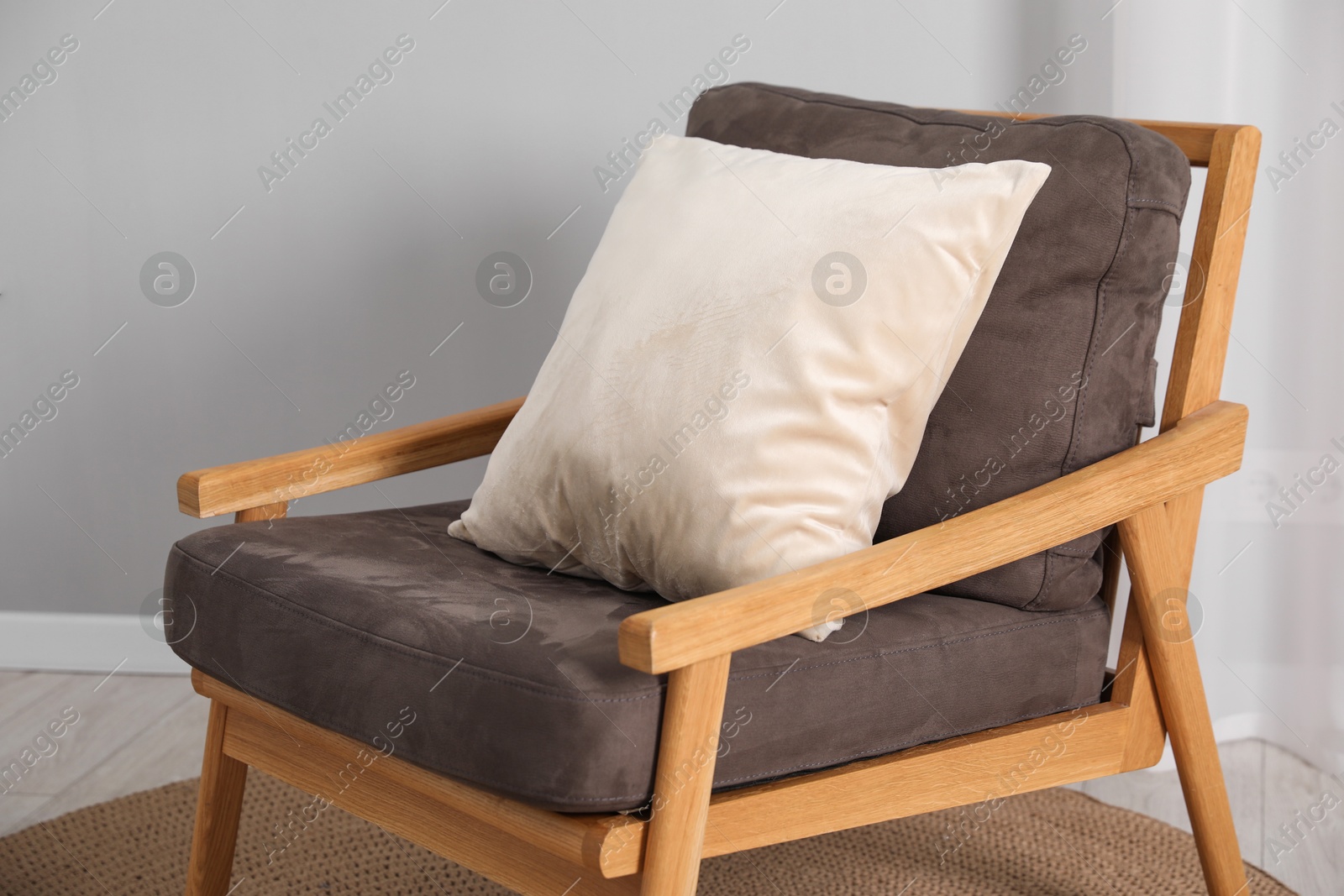 Photo of Soft armchair with pillow on floor indoors