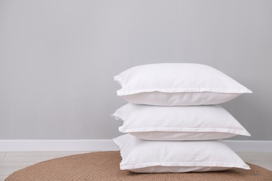 Photo of Stack of white pillows on floor indoors. Space for text