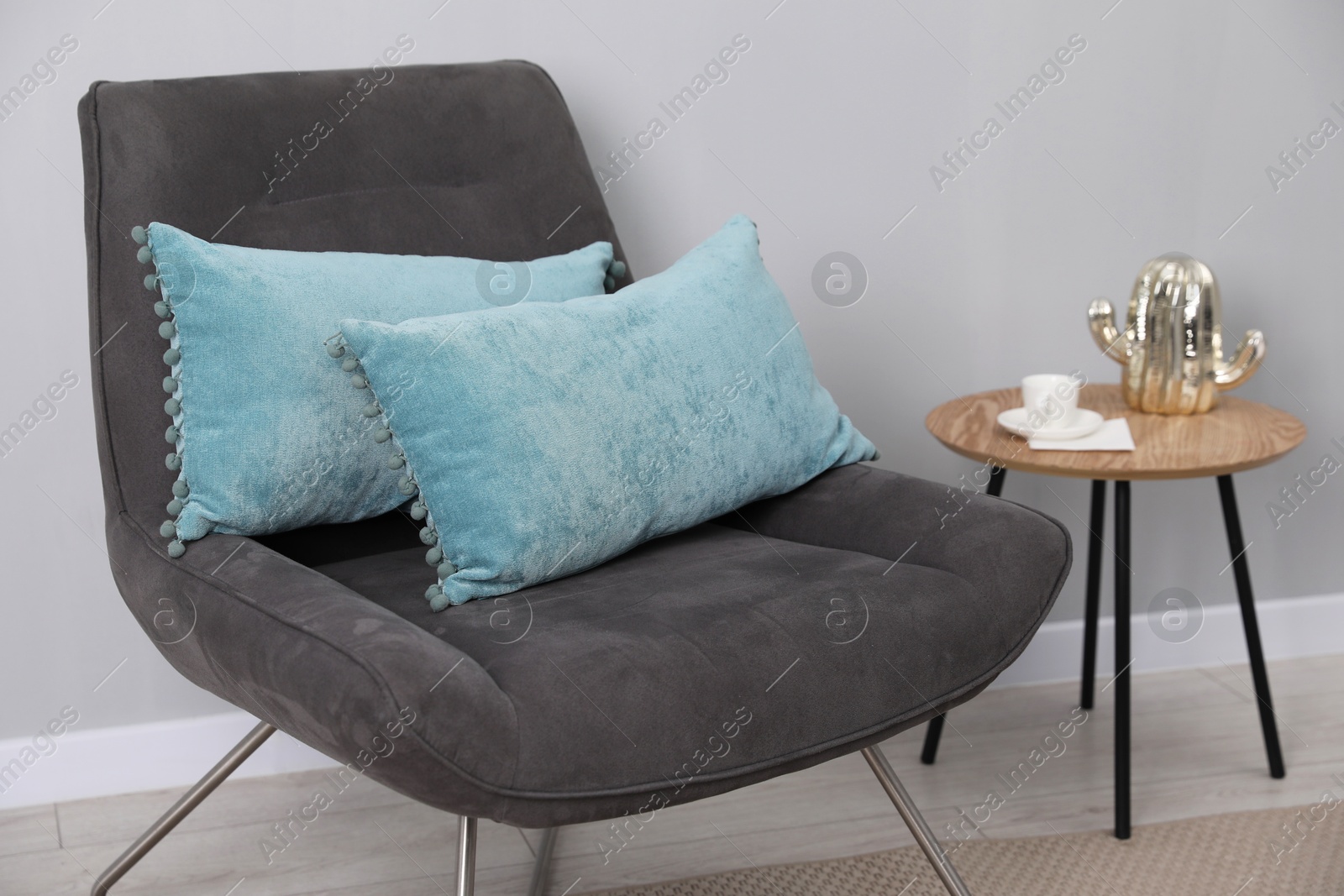 Photo of Soft pillows on armchair near coffee table indoors