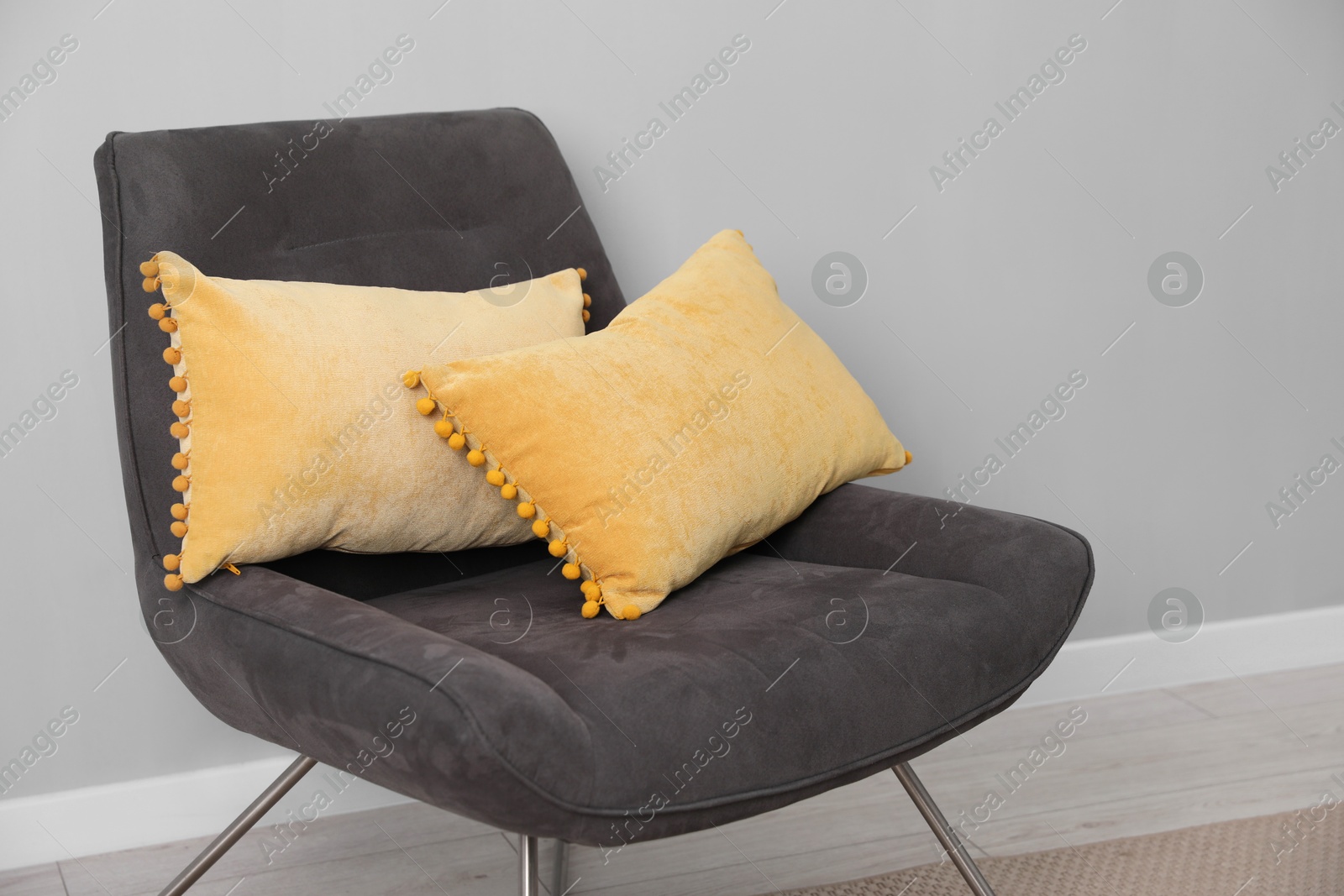 Photo of Soft armchair with pillows on floor indoors