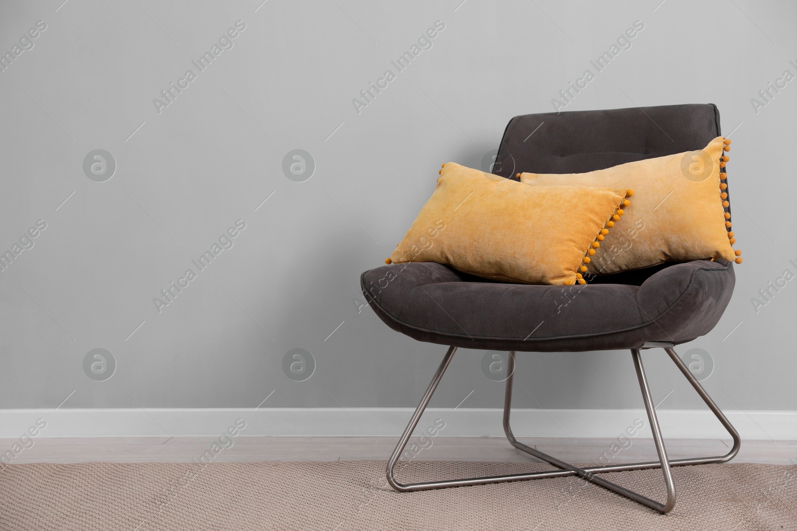 Photo of Soft armchair with pillows on floor indoors. Space for text