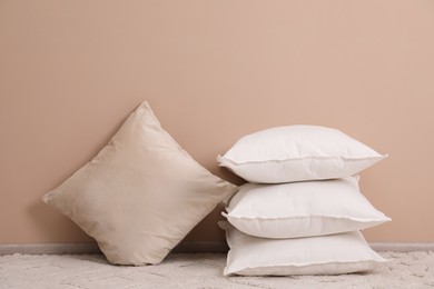 Photo of Soft pillows on floor near beige wall