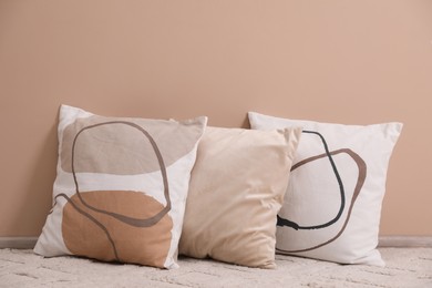 Photo of Soft pillows on floor near beige wall