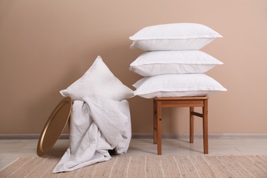 Photo of Stack of pillows, stool, storage basket and blanket on floor indoors