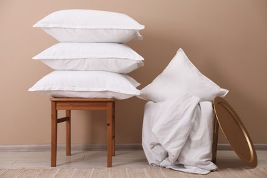 Photo of Stack of pillows, stool, storage basket and blanket on floor indoors