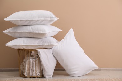 White pillows, storage basket and blanket near beige wall. Space for text