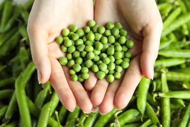 Photo of Woman holding fresh green peas near pods, closeup