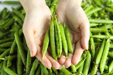 Photo of Woman holding fresh green pea pods, closeup