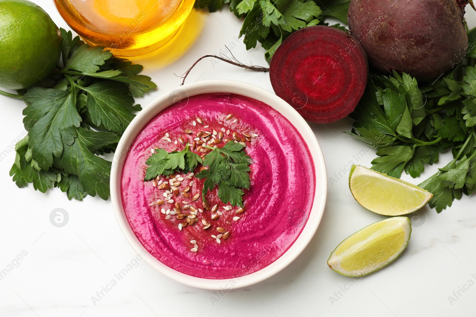 Photo of Tasty beetroot hummus in bowl and products on white marble table, flat lay