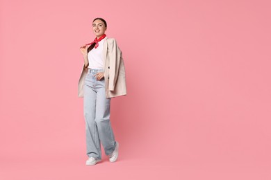 Stylish woman in beige jacket and jeans on pink background, space for text