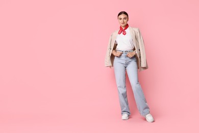 Stylish woman in beige jacket and jeans on pink background, space for text