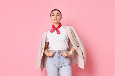 Stylish woman in beige jacket and jeans on pink background