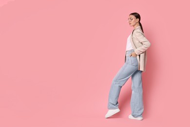 Photo of Stylish woman in beige jacket and jeans on pink background, space for text